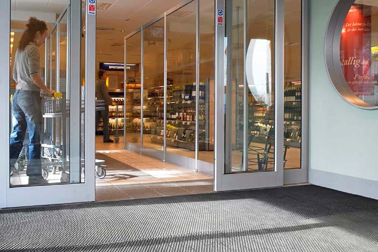 Entré till butik med glasdörrar och tålig skrapmatta som tar bort smuts från sko