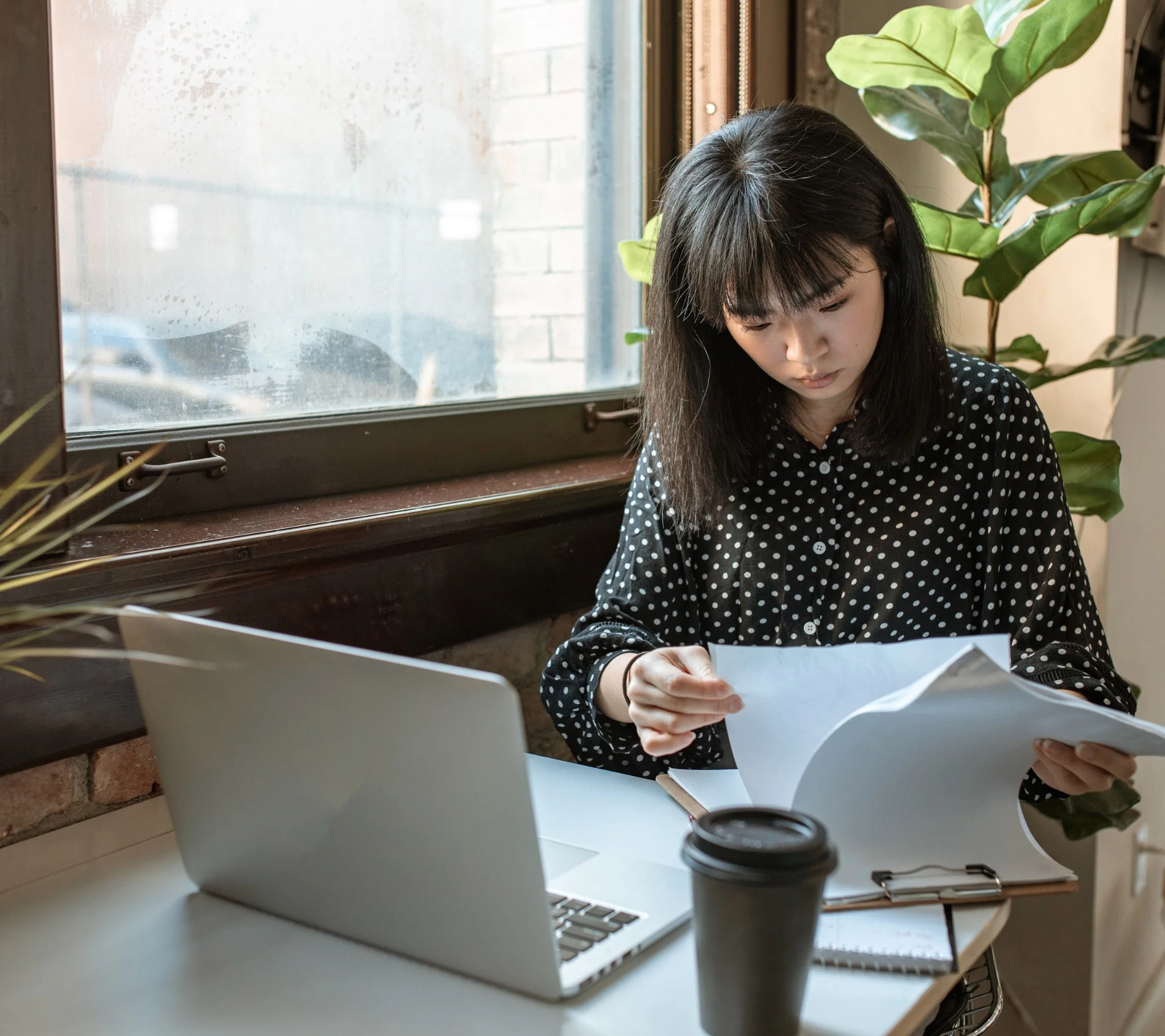 Kvinna sitter vid skrivbord med laptop och dokument, planerar och koordinerar projektledning inför företagsflytt. Bilden illustrerar Joyweeks professionella planering och struktur vid kontorsflyttar för företag