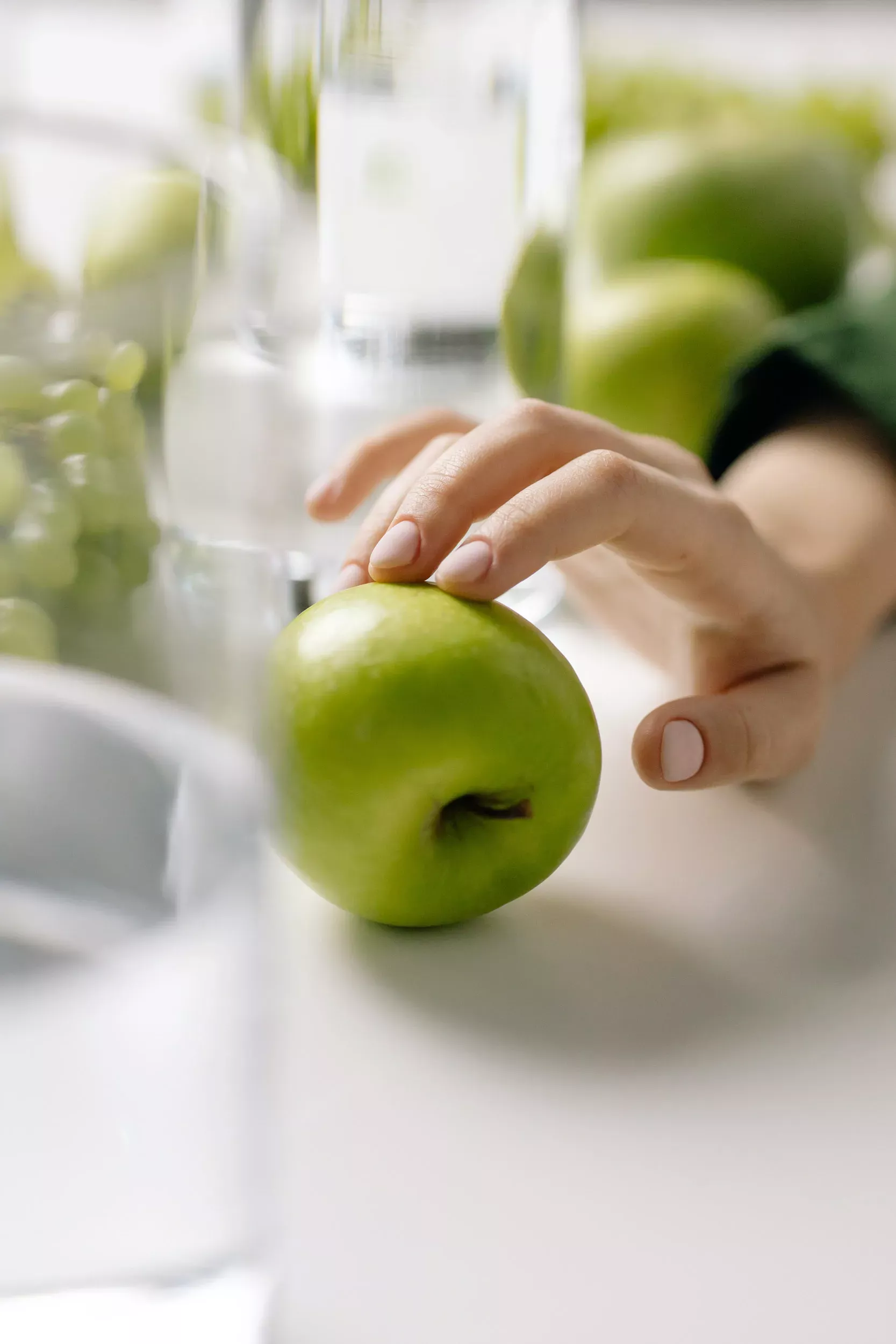Hand som tar ett grönt äpple ur en fräsch fruktkorg, del av företagets fruktkorgar för arbetsplatser