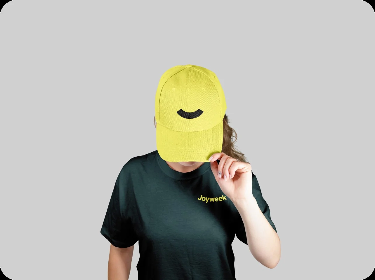 Person som bär en gul keps och en svart t-shirt med texten ”Joyweek” mot grå bakgrund
