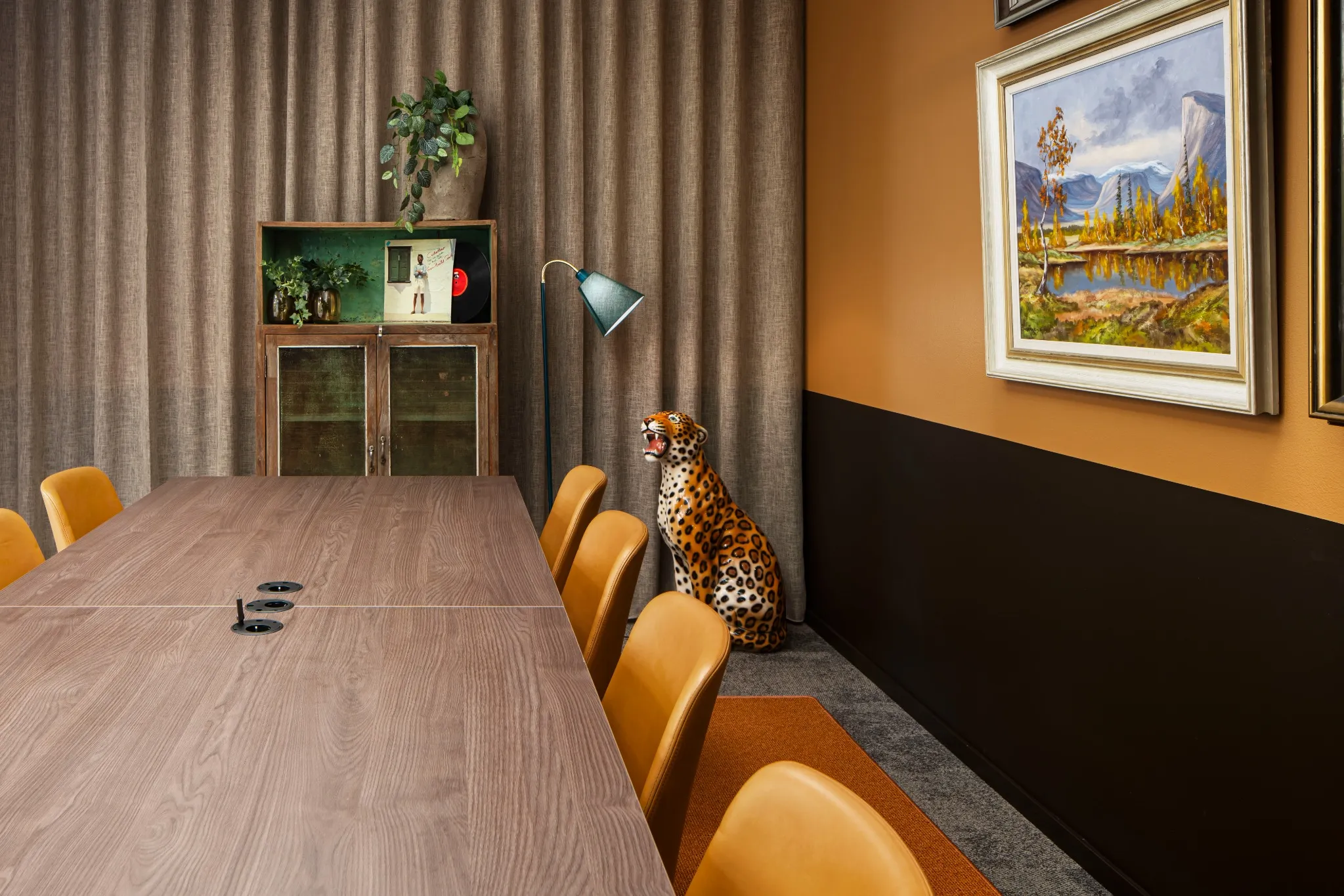 Kreativ och färgstark möteslokal med konferensbord, gula stolar och dekorativ leopardfigur