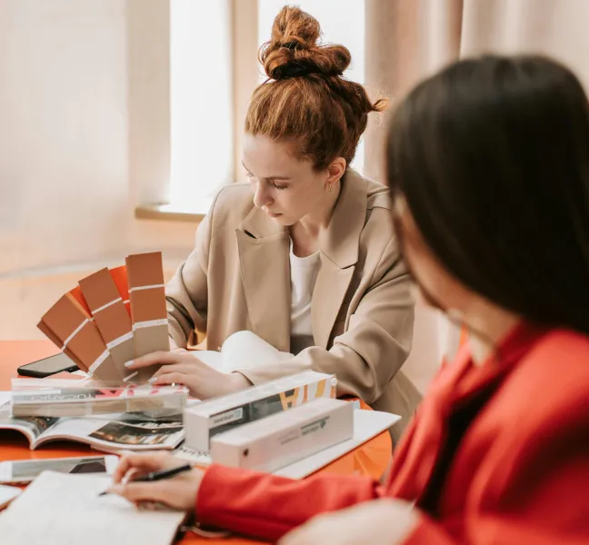 Två personer vid ett bord granskar färgprover och designmaterial